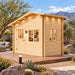 Wide front-right view of the 67-square-foot Bluewater Den Freedom Office in a sunny Nevada backyard. One adult works inside the compact office, surrounded by desert plants, boulders, a wooden platform, and distant mountains.
