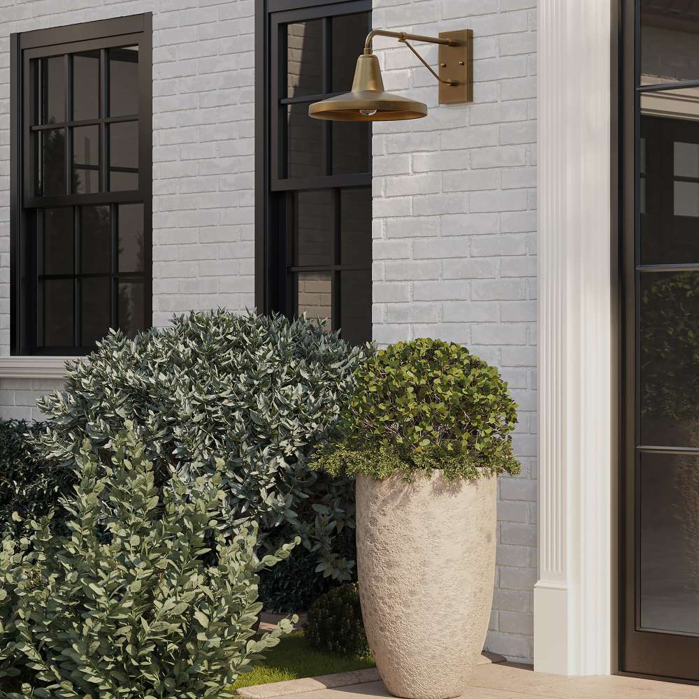 Brass Crate & Barrel Mariner Outdoor Wall Sconce shown from an angle to reveal the faceted shade and cantilever bracket