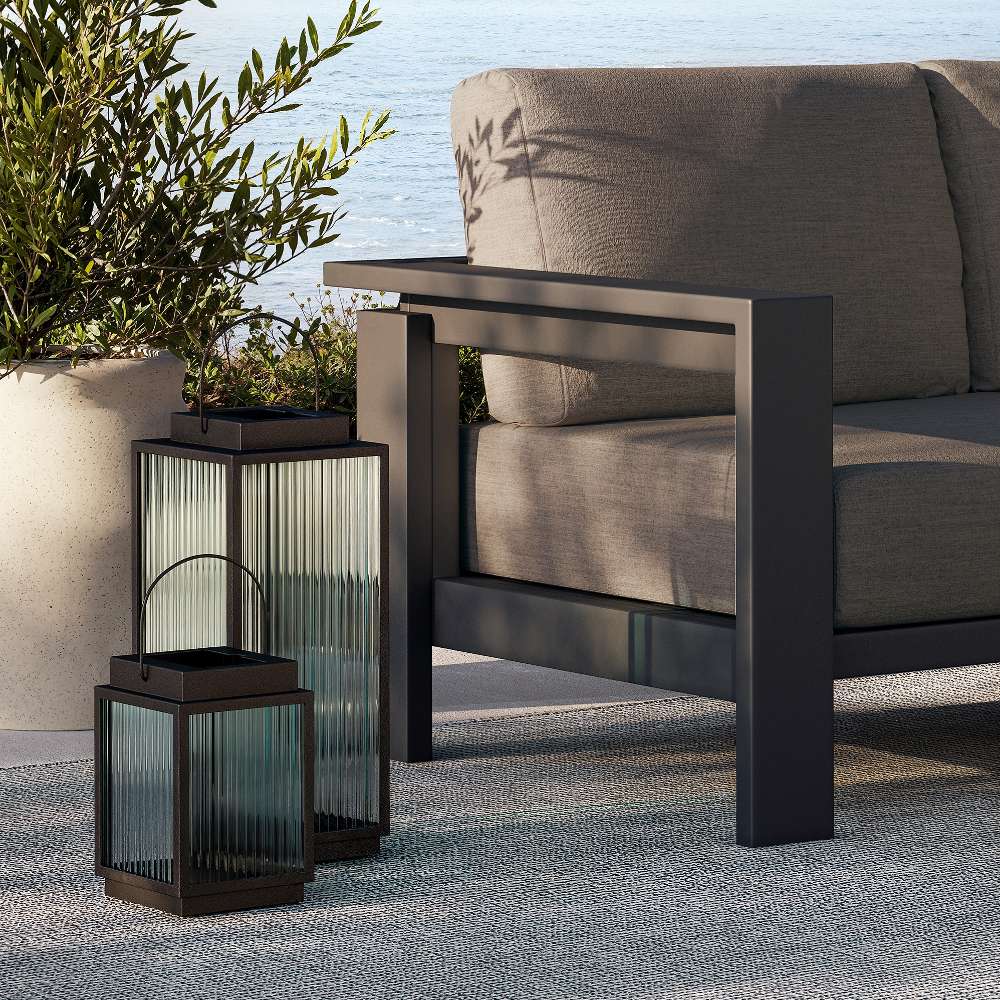 Close up detail of the Crate & Barrel Alfresco Black Metal and Glass LED Solar Outdoor Lantern showing the reeded glass and black steel frame