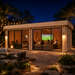 Rectangular wood studio with glass sliding doors at night, showing people watching a screen inside the Lasse 44A ALU.