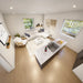 Top-down view inside the Jasper Garden Suites showing an open-concept living area with a marble kitchen island, white sectional sofa, armchair, and large windows.