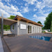 Angled view of the modern Jasper Garden Suites with gray cladding, a wood deck, plunge pool, sliding glass doors, and a pergola-covered lounge area.