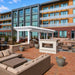 White Structureworks Trex Pergola in a landscaped apartment courtyard with grills, lounge seating, dining tables, and a modern fire feature.