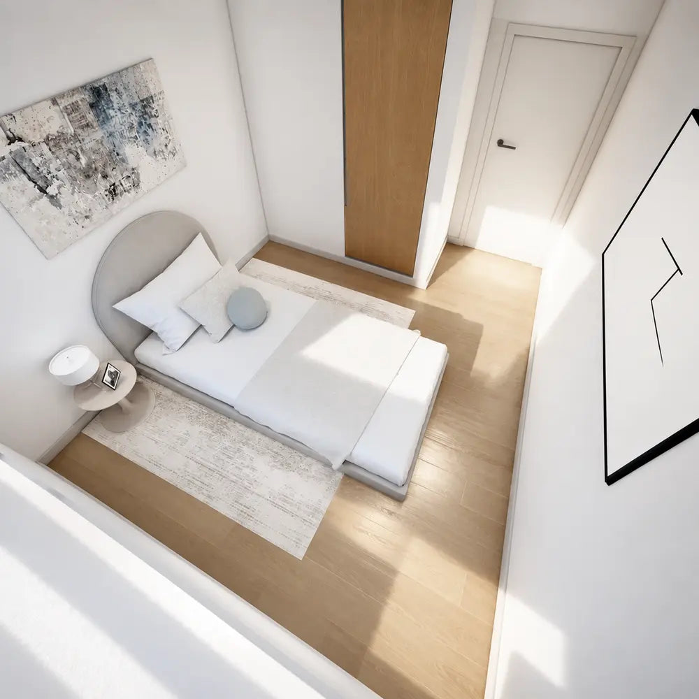 Compact bedroom inside the Banff Garden Suites with minimalist furnishings, neutral bedding, light wood flooring, and clean modern finishes.