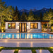 The illuminated Tremblant one-bedroom Freedom Suite on a bright Colorado summer night, with adults watching sports through the front window as the pool glows beneath a starry sky and Rocky Mountains.