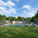 Wide view of the Jasper Garden Suites surrounded by a long pool, lush landscaped gardens, hanging chairs, lounge areas, and outdoor fire features.