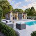 Modern Muskoka Garden Suites guest suite with large glass doors overlooking a sparkling pool, fountain jets, woven seating, and landscaped gardens.