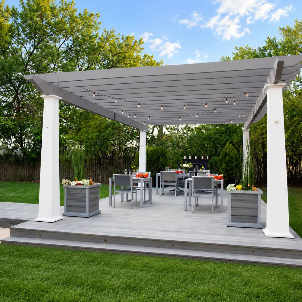 Two-tone Structureworks Trex Pergola with white posts, gray rafters, string lights, planters, and modern outdoor dining furniture.