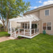 Classic white Structureworks Trex Pergola attached to a house above a raised backyard deck with stairs, railings, and outdoor seating.