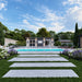 Centered front view of the Muskoka Garden Suites with clean architectural lines, a central pool, fountain jets, lounge chairs, pathway lights, and lush landscaping.