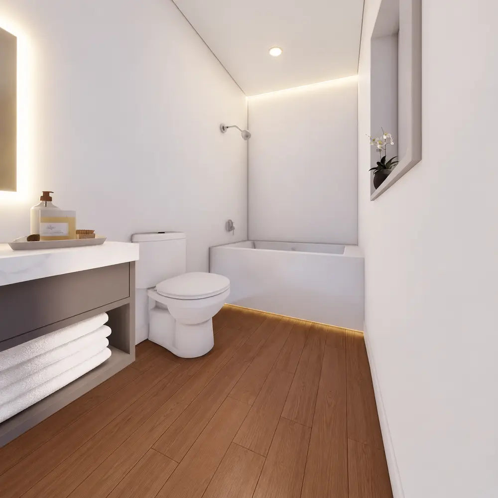 Modern white bathroom in the Muskoka Garden Suites with a bathtub, toilet, floating vanity, folded towels, wood flooring, and soft under-cabinet lighting.