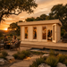 Rectangular light wood studio with glass doors on a deck at sunset, featuring a lit interior bar and outdoor seating.