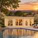 Straight-on view of the Henning 70 entertainment bar beside a reflective pool at golden hour, overlooking flowering dogwoods, Piedmont farmland, and wooded North Carolina ridges.