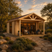 Small wood studio with a gabled roof and glass doors, featuring a front porch and stone walkway at sunset.