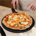 Gozney 14" Pizza Server held by a person in an apron on a countertop with a baked margherita pizza resting on it.