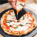Gozney 14" Pizza Server with a hand lifting a slice from a margherita pizza resting on the round charcoal surface.