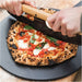 Gozney 14" Pizza Server with two hands cutting a margherita pizza on it using a rocker blade with a wooden handle.