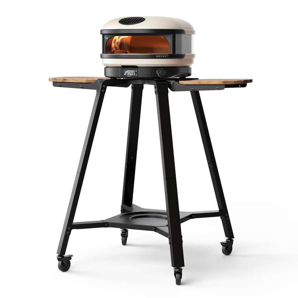 Gozney Arc Pizza Oven Stand angled view on white with a Bone Arc pizza oven on top two wooden side shelves a lower shelf and four casters.