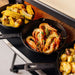 Gozney Dome 2 Mantel loaded with cast iron pans of grilled corn shrimp and potatoes at the mouth of a Dome oven.