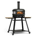 Gozney Dome Gen 2 Natural Gas Pizza Oven on white on its rolling stand with wooden side shelves and casters a flame inside the dome and the chimney fitted on top.