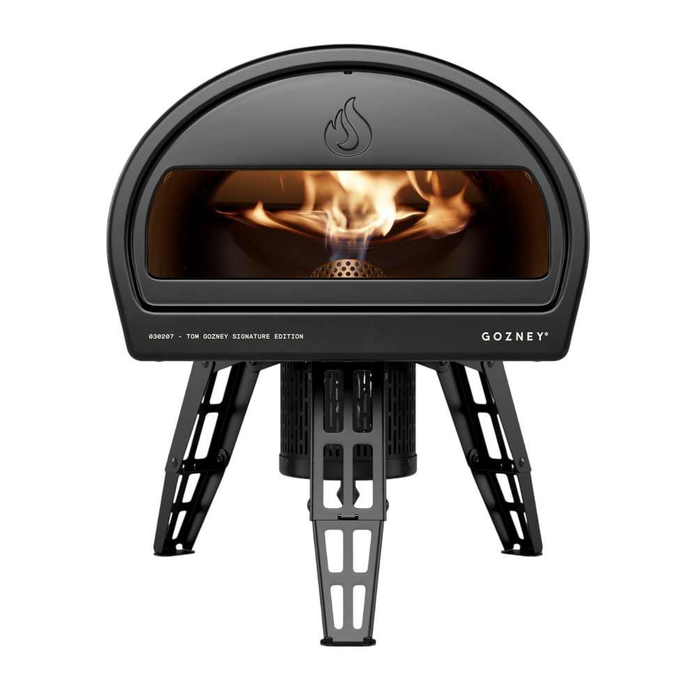 Gozney Roccbox Black Outdoor Portable Pizza Oven front view on white with a wood fire burning on the stone floor inside the arched mouth and the folding legs extended.