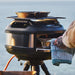 Gozney Tread Roof Rack loaded with two pans of food on top of a Tread oven on its tripod stand with the sea behind.