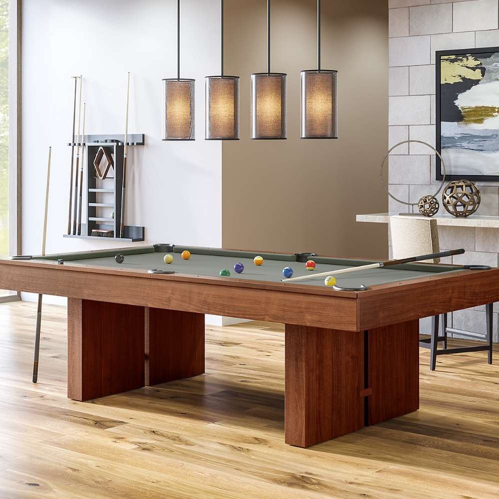 Grey Crate & Barrel Walnut Pool Table with Wall Rack and Accessories at an angle in a game room under four pendant lights with coloured balls on the grey felt and a wall cue rack behind