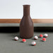 Grey Crate & Barrel Walnut Pool Table with Wall Rack and Accessories in close up on a brown shake bottle standing on the grey felt with small numbered red and white peas scattered around it