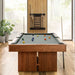 Grey Crate & Barrel Walnut Pool Table with Wall Rack and Accessories seen end on in a room with floor to ceiling windows onto woodland, coloured balls on the grey felt and a cue rack on the wall behind