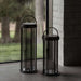 Gunmetal Crate & Barrel Blomus Mituro Rechargeable LED Indoor/Outdoor Lantern shown in a styled setting, a cylindrical tower lamp with a darkened glass shade