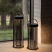 Gunmetal Crate & Barrel Blomus Mituro Rechargeable LED Indoor/Outdoor Lantern shown in a styled setting, cordless and lit from the top and bottom of the glass shade