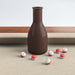 Khaki Crate & Barrel Walnut Pool Table with Wall Rack and Accessories in close up on a brown shake bottle standing on the khaki felt with small numbered red and white peas scattered around it