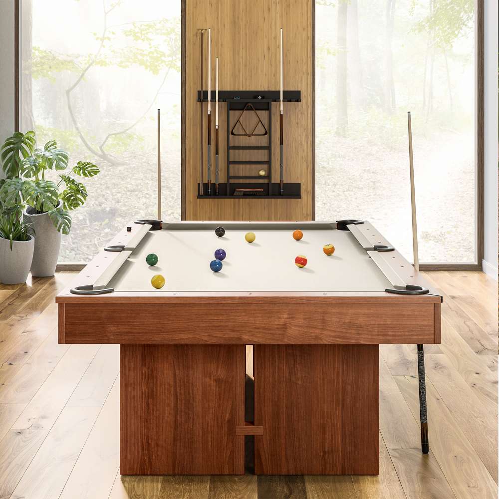 Khaki Crate & Barrel Walnut Pool Table with Wall Rack and Accessories seen end on in a room with floor to ceiling windows onto woodland, coloured balls on the khaki felt and a cue rack on the wall behind