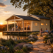 Exterior view at sunset of the Lake House 70A cabin positioned next to a calm lake, featuring warm indoor/outdoor lighting, a covered porch bar, and people relaxing around an outdoor stone fire pit.
