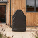 Large Ooni Table and Pizza Oven Cover standing tall over a table on a patio beside a timber clad house with a glass door.