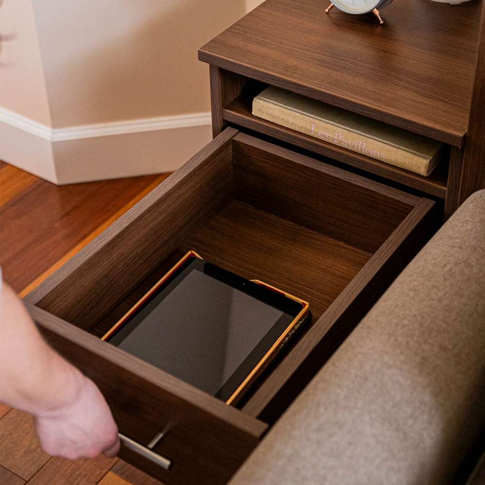 Modern Walnut Inovabed Wall Bed with Sofa and Two Nightstands in close-up with a hand pulling the nightstand drawer open to reveal a tablet inside