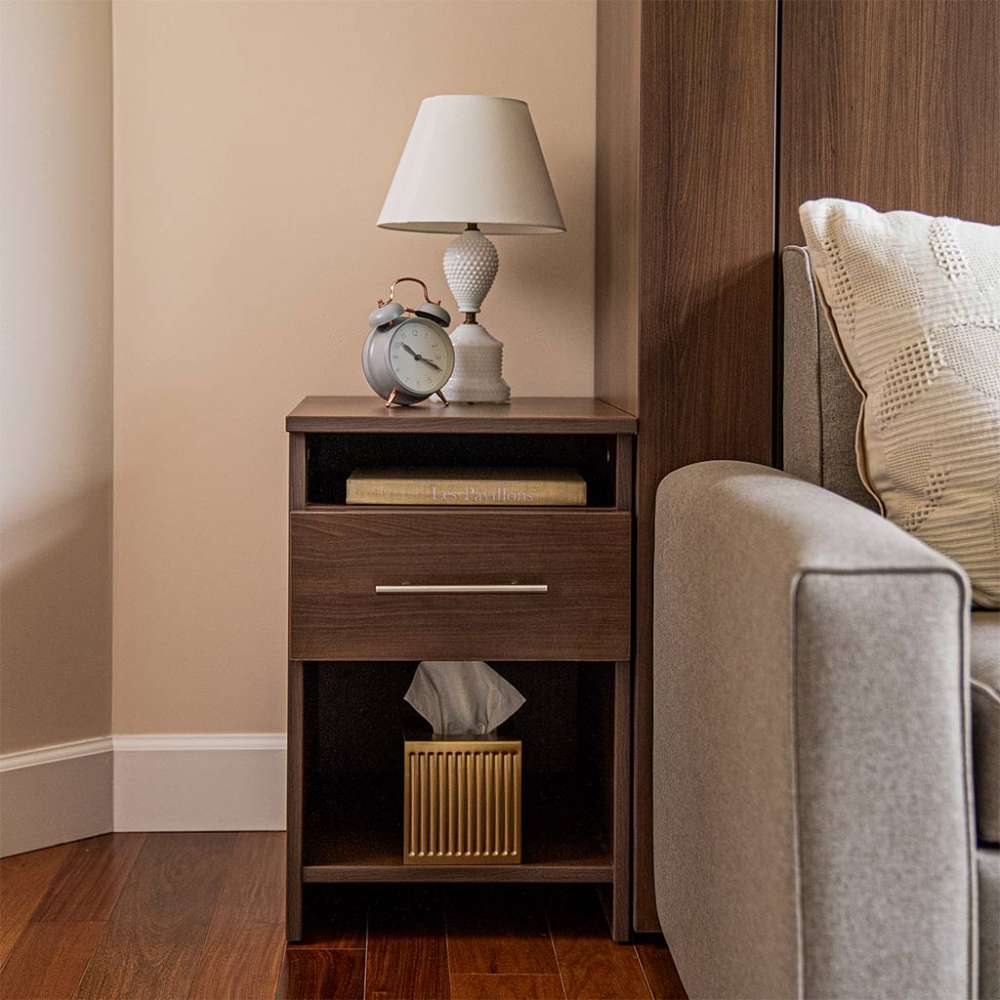 Modern Walnut Inovabed Wall Bed with Sofa and Two Nightstands showing one nightstand beside the bed with a lamp, an alarm clock and a gold tissue box on the lower shelf