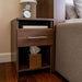 Modern Walnut Inovabed Wall Bed with Sofa and Two Nightstands showing one nightstand beside the bed with a table lamp, an alarm clock, a book in the cubby and a tissue box on the lower shelf