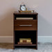 Modern Walnut Inovabed Wall Bed with Sofa and Two Nightstands showing one nightstand topped with an alarm clock on a brass tray, books in the cubby and more books on the lower shelf