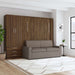 Modern Walnut Inovabed Wall Bed with Sofa and Wide Flex Cabinet closed as a gray sofa in a bright room beside the Wide Flex Cabinet, with a round side table alongside
