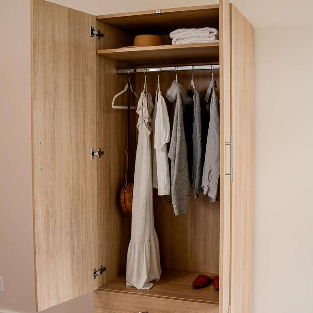 Natural Oak Inovabed Wall Bed with Table and Two Narrow Flex Cabinets showing a cabinet interior with clothes on a wardrobe rod and folded towels and a hat on the shelf above