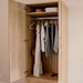 Natural Oak Inovabed Wall Bed with Table and Two Narrow Flex Cabinets showing a cabinet interior with clothes on a wardrobe rod and folded towels and a hat on the shelf above
