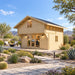 Front-right view of the 225-square-foot Northwood Grand DD 70mm Freedom Loft Studio in a sunny Nevada backyard. An adult works inside the compact office, surrounded by desert plants, boulders, pathway lights, outdoor seating, and distant mountains.
