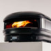 Off-Black Gozney Arc XL Pizza Oven close view on a pale countertop with a tall orange flame filling the copper-toned dome and the control dial in the foreground.