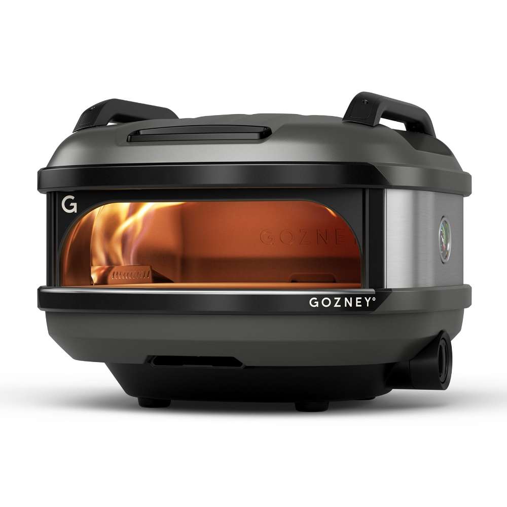 Off-Black Gozney Tread Pizza Oven angled front view on white with a flame inside the copper-toned dome and the two black carry handles on top.