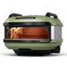 Olive Gozney Tread Pizza Oven angled front view on white with a flame inside the copper-toned dome the green shell and a rear wheel visible.