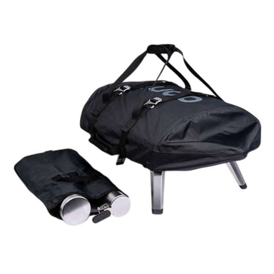Ooni Fyra Outdoor Pizza Oven Carry Cover zipped over the oven with a padded shoulder strap and buckled straps on top, the stainless steel legs showing below, and a separate black drawstring bag holding the chimney in front.