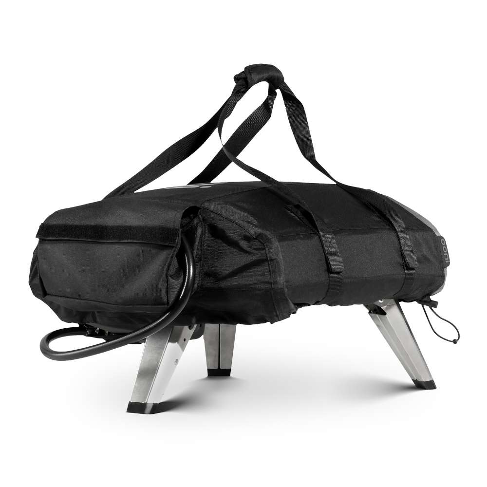 Ooni Koda 2 Carry Cover fitted over an oven seen from the rear right in all black with the ooni logo, carry straps over the top and the gas hose looped out below.