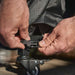 Ooni Table and Pizza Oven Cover close view of two hands clipping the buckle strap around a table caster.