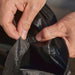 Ooni Table and Pizza Oven Cover close view of two hands fastening a press stud on the hem beside the zip.